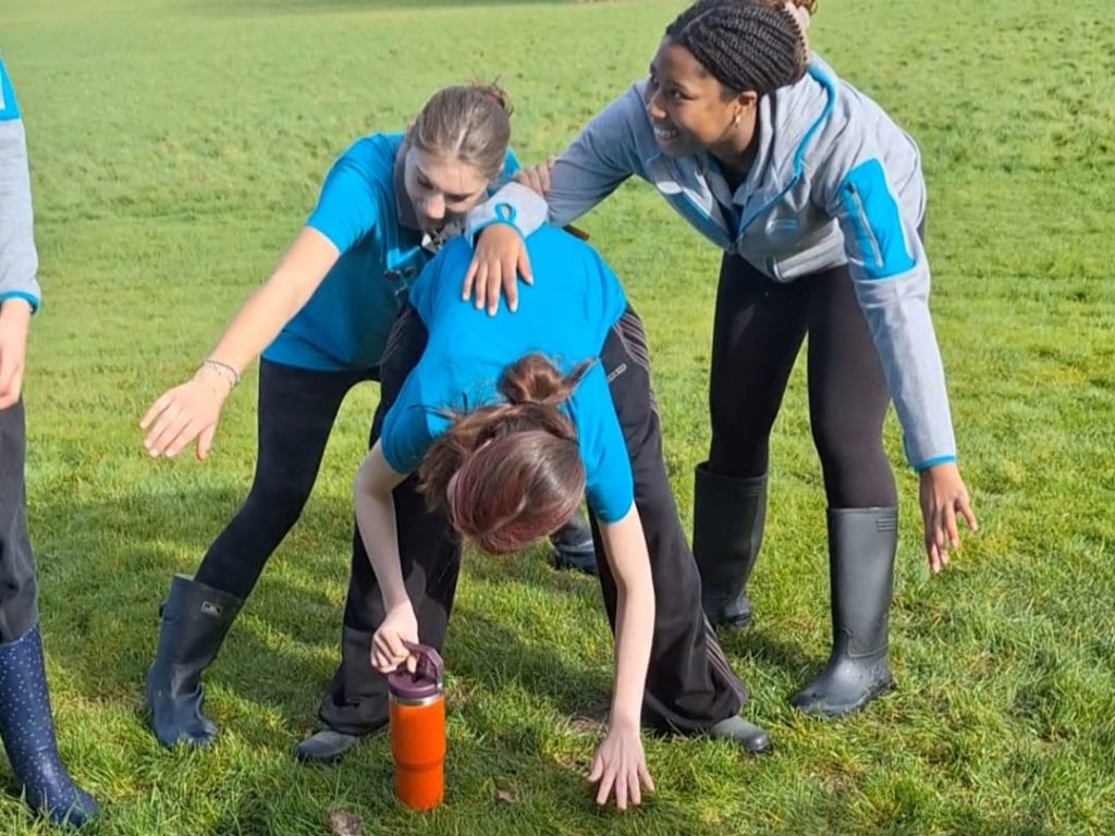 Three girls bending over with their arms outstretched as they play a game.