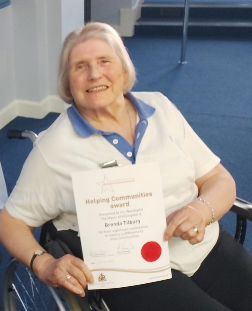 Grey haired woman in white Girlguiding Leader polo shirt holding a certificate. T