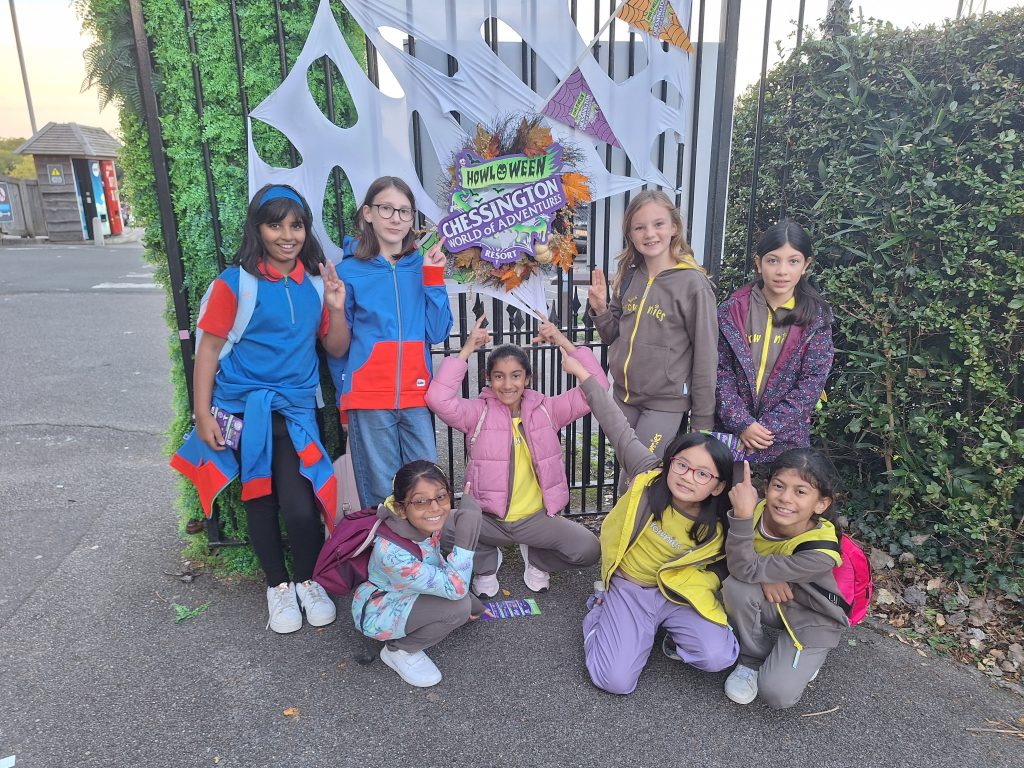 Six Brownies and two Guides standing and kneeling in front of a Chessington sign.