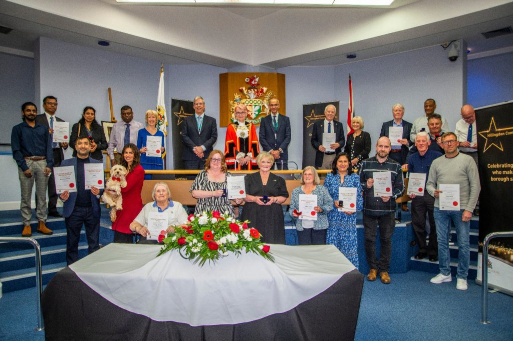A number of people gathered in a room holding certificates.