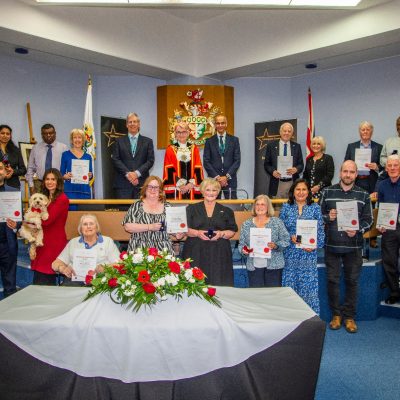 A number of people gathered in a room holding certificates.