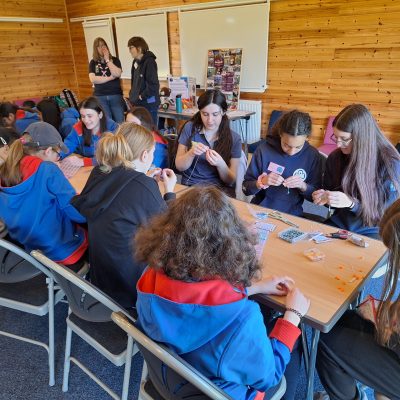Guides and Rangers sitting around a long table making their beaded bracelets.